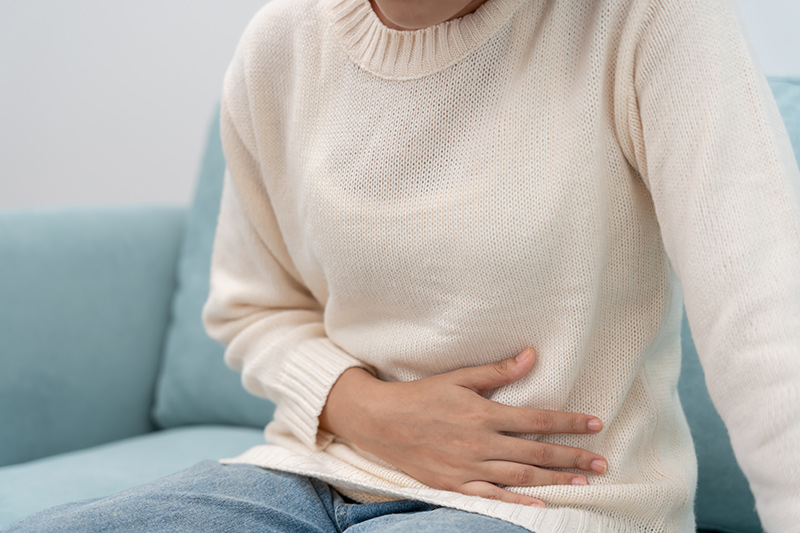 Woman holding her abdomen indicating abdominal pain.