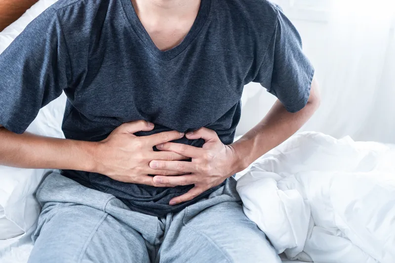 Man experiencing stomach pain while holding his abdomen