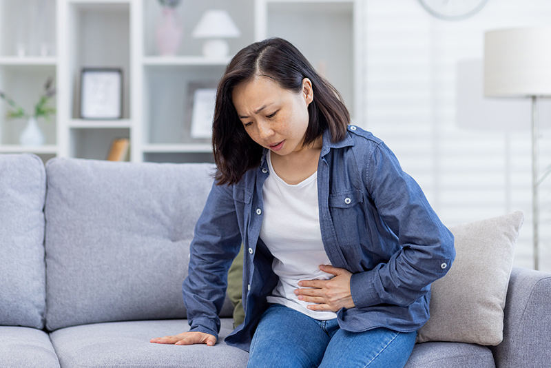 Woman holding her abdomen in discomfort, indicating abdominal pain.