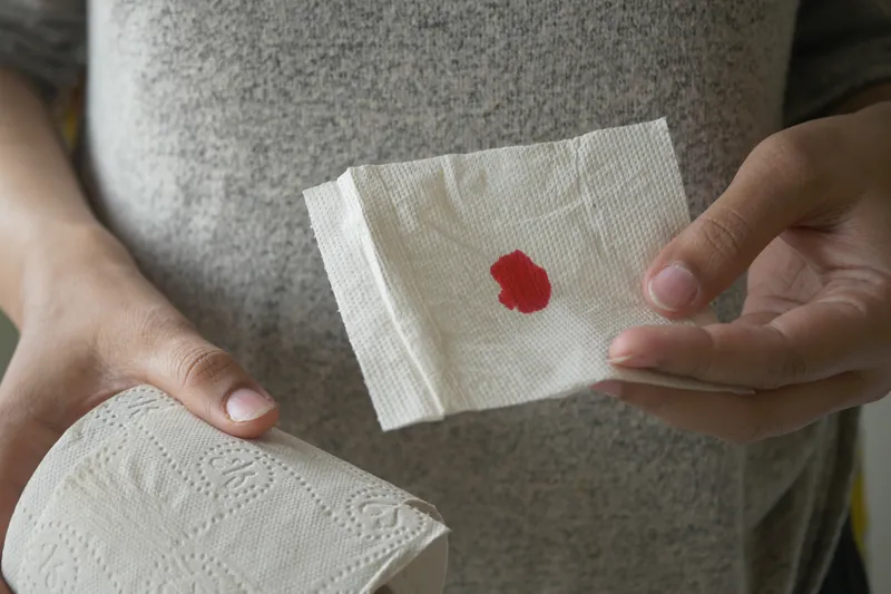 Person holding a tissue with blood, indicating possible rectal bleeding