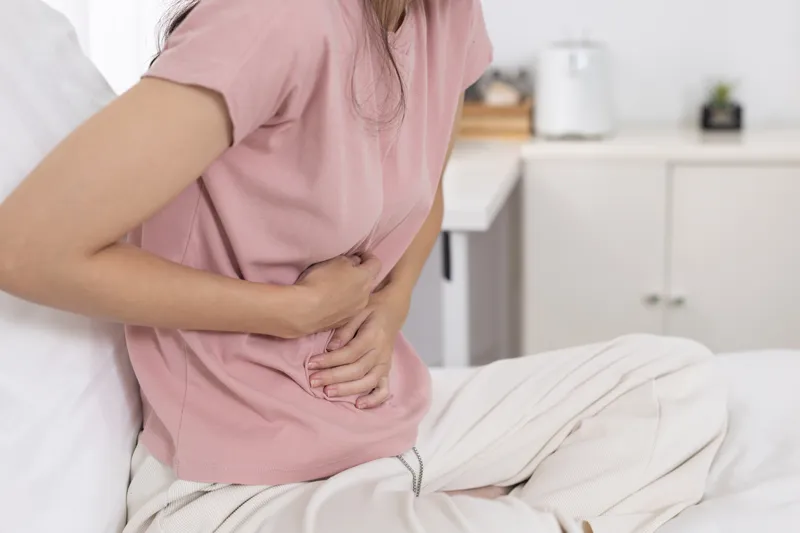 Woman holding her lower abdomen while experiencing abdominal pain