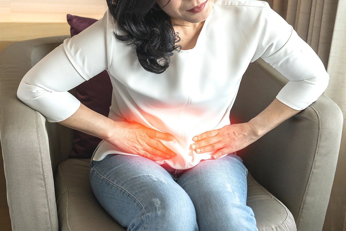 Woman holding her abdomen in pain associated with a hernia.