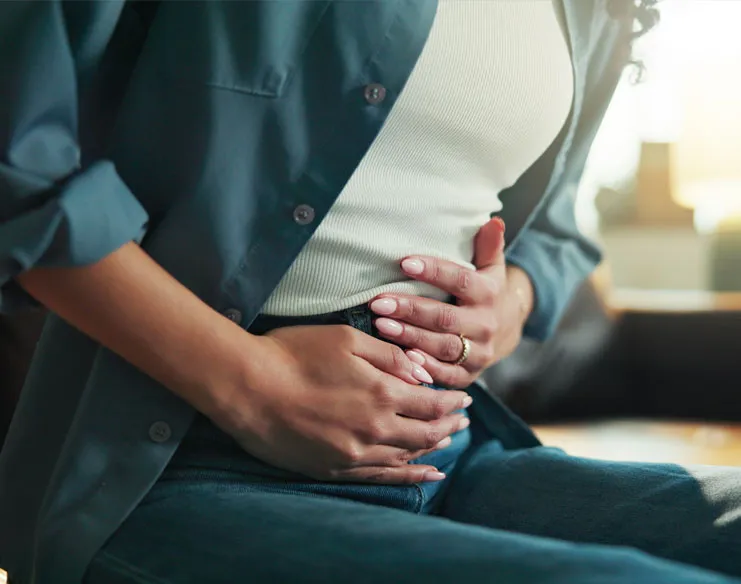 Woman experiencing abdominal discomfort, indicating symptoms of inflammatory bowel disease.