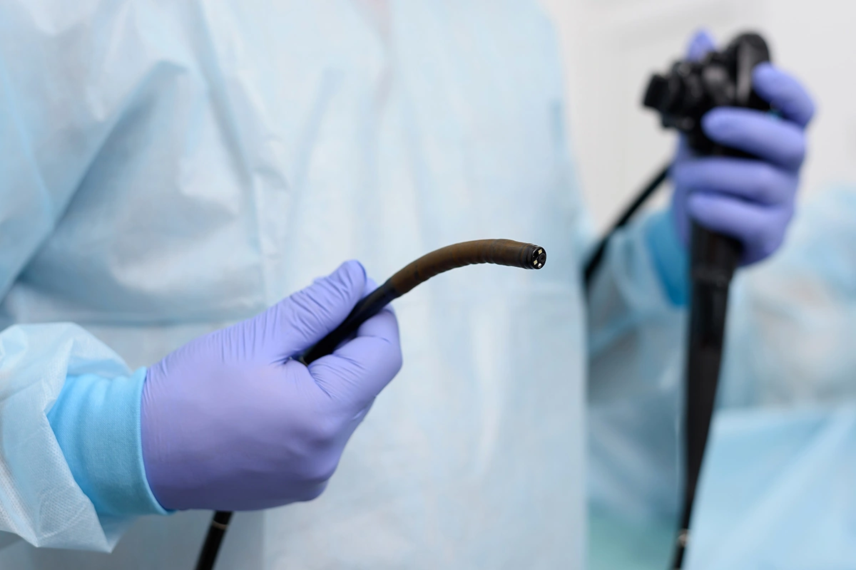 Doctor holding endoscopic instruments for a colonoscopy procedure.