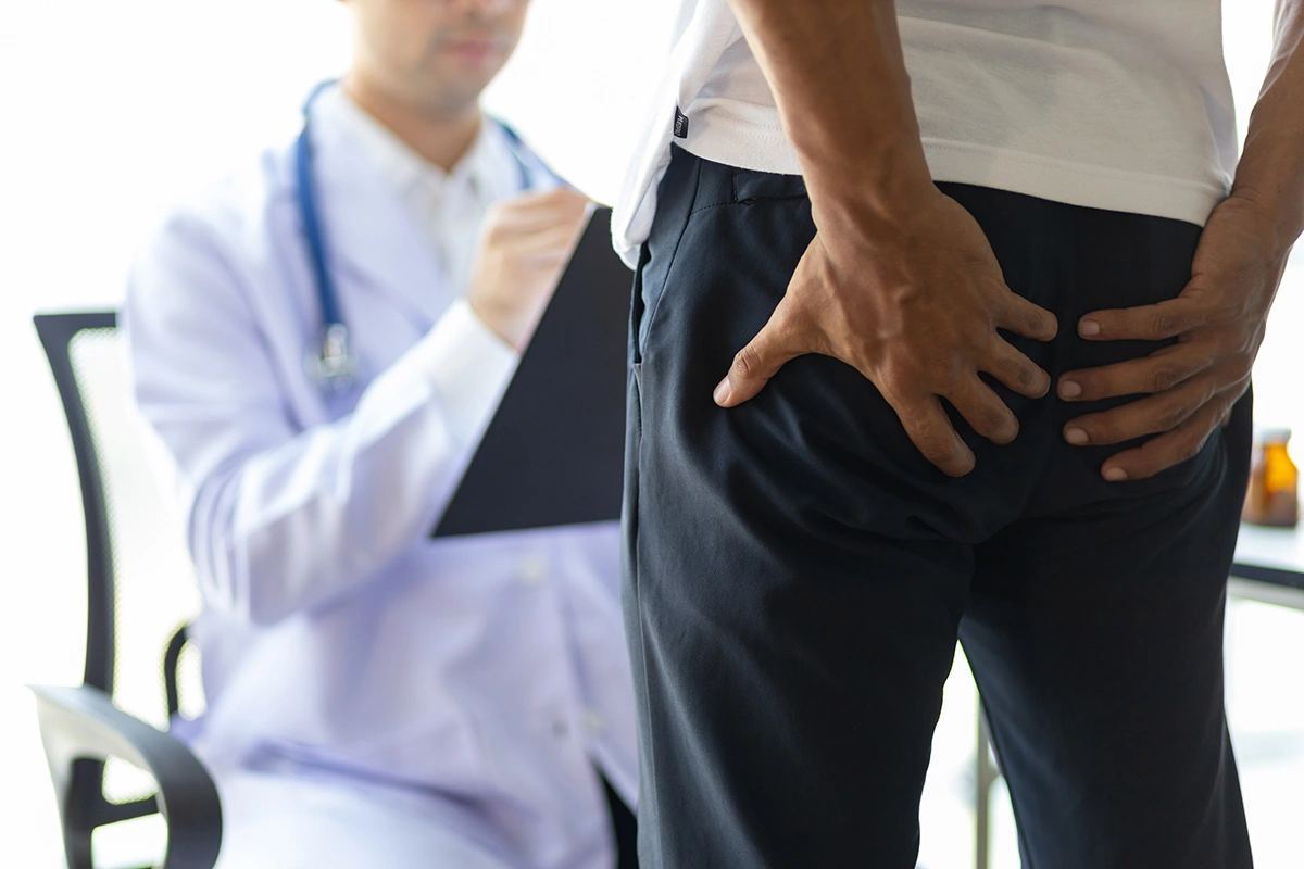 Man at a medical consultation with a doctor, discussing symptoms and piles treatment options in a clinic setting. 