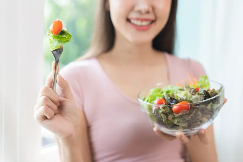 Woman enjoying a bowl of salad with fibre-rich vegetables