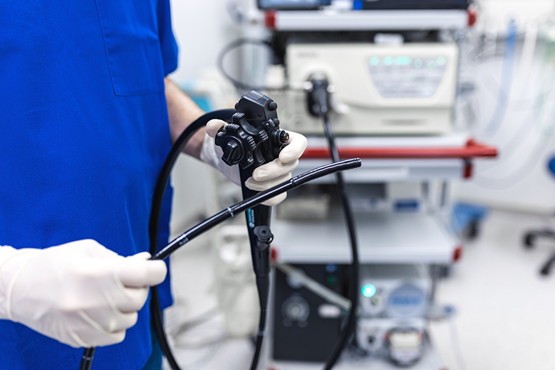 Doctor preparing for a gastroscopy in a clinical procedure room.