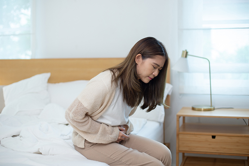 Woman experiencing abdominal pain and holding her stomach.