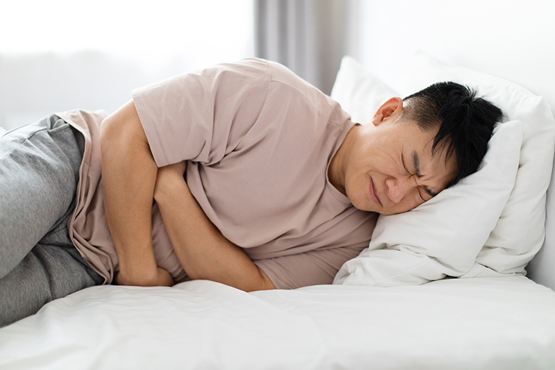 Man holding his abdomen in discomfort, indicating abdominal pain or digestive issues.